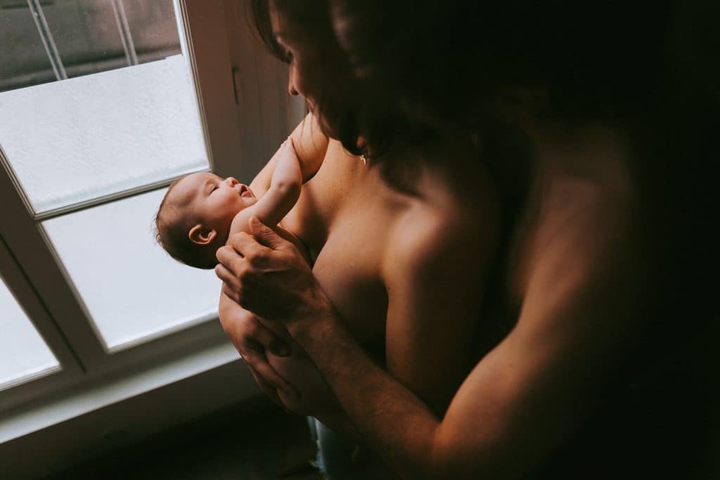 Couple avec leur nouveau-né en peau à peau dans un appartement, capturé par une photographe dans les Landes et le Pays Basque